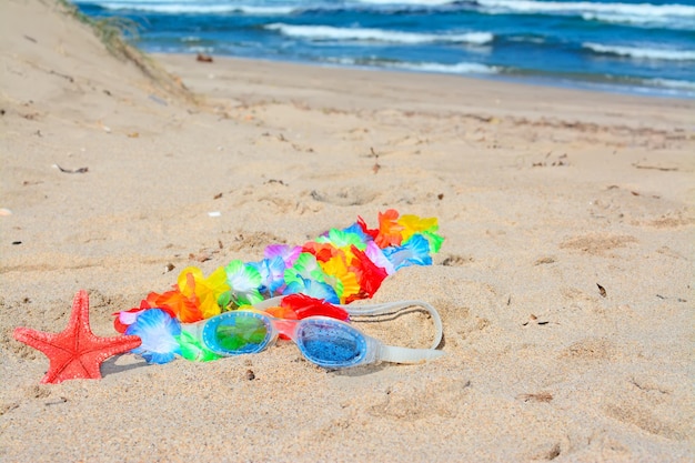 Colar havaiano e óculos de praia na areia