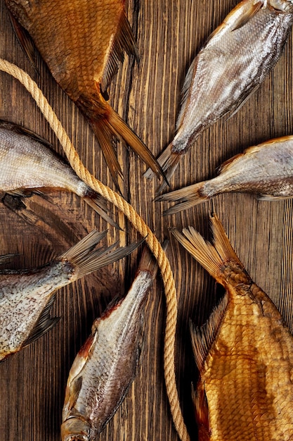 Colas de pescado ahumado y seco salado de diferentes tamaños sobre la superficie de madera con cuerda