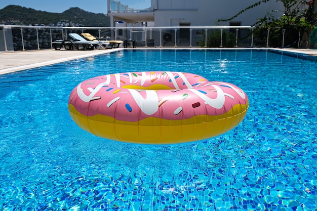 Colchão flutuante rosa donut donut na piscina. Acessórios para piscinas de praia. Conceito de férias de verão.