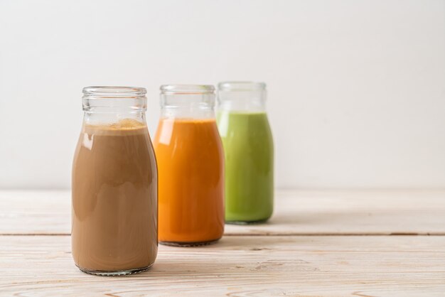 Coleção de bebida de chá com leite tailandês, chá verde matcha com leite e café em garrafa com fundo de madeira