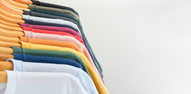 Foto coleção de camisetas coloridas penduradas em um cabide de madeira no armário sobre fundo branco