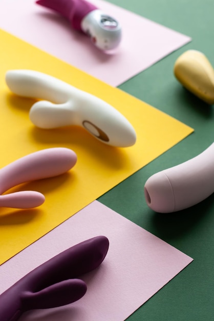 Foto coleção de diferentes tipos de brinquedos sexuais em um fundo rosa verde e amarelo