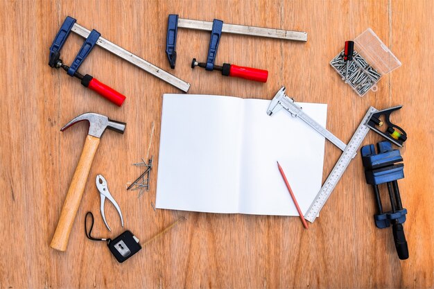 Foto coleção de ferramentas de trabalho, conjunto de ferramentas de trabalho. (chave de aço, martelo, pregos, parafusos, chaves, etc.) com caderno na mesa de madeira.