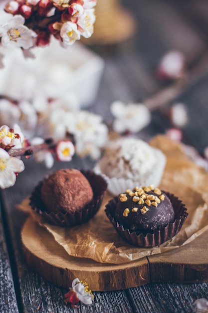 Coleção de primavera de bombons de chocolate artesanal e decoração de flores de cerejeira em fundo de madeira rústica