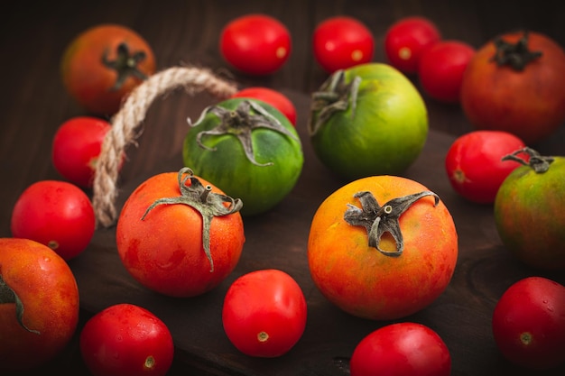 Coleção de tomates coloridos inteiros servidos em uma natureza morta de tomates de fundo de madeira