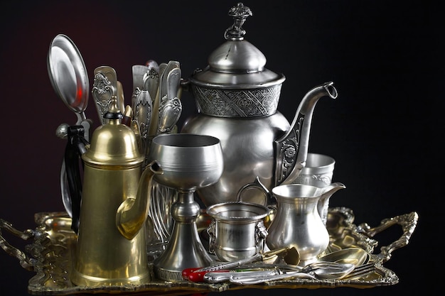 Una colección de artículos de plata y oro que incluyen una taza, una taza y una cuchara.