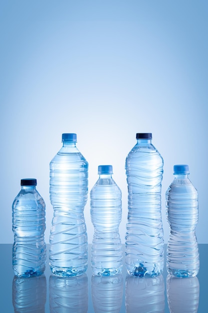 Colección de botellas de agua aisladas sobre fondo azul con espacio de copia Formato vertical