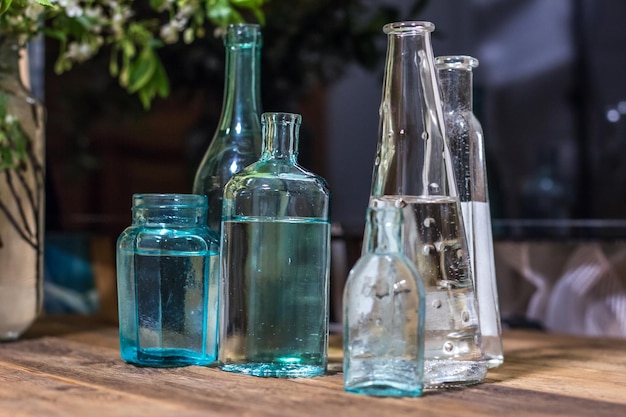 Una colección de botellas de vidrio sobre una mesa de madera.