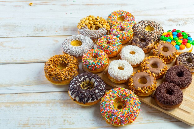 Colección de deliciosas donas en tablero de madera blanca