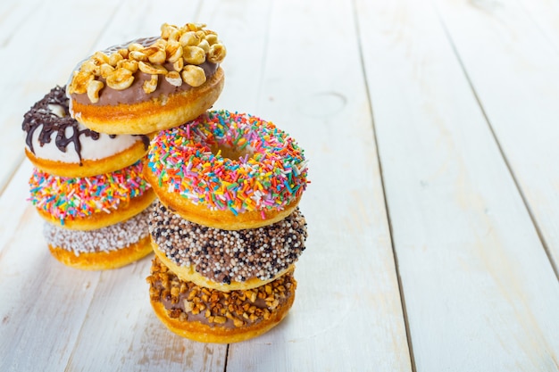 Colección de deliciosas donas en tablero de madera blanca