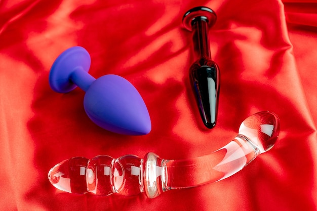 Una colección de diferentes tipos de juguetes sexuales en satén rojo.
