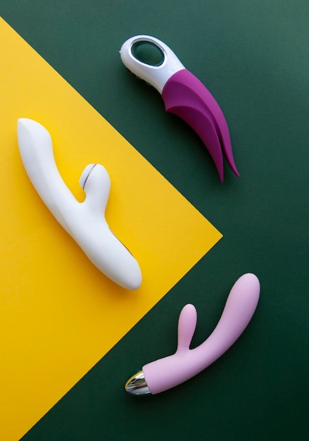 Colección de diferentes tipos de juguetes sexuales sobre un fondo verde y amarillo Juguetes sexuales para adultos consoladores vibradores estimuladores del clítoris