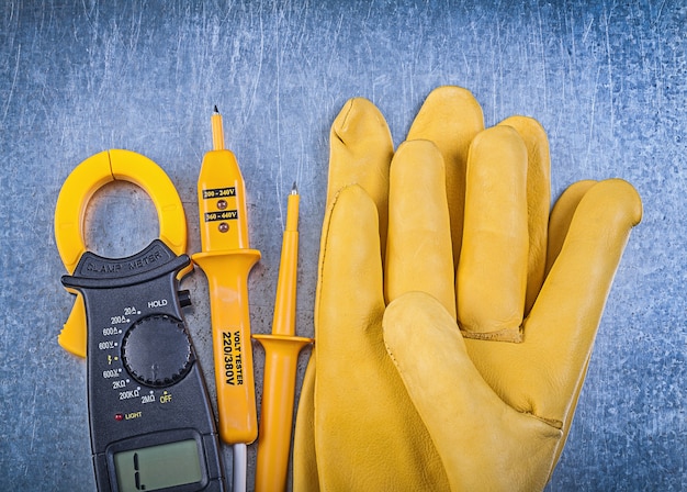 Colección de guantes de seguridad probador eléctrico medidor de pinza digital en superficie metálica