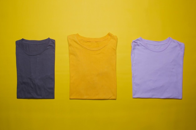 Foto colección de maquetas de camisetas dobladas sobre fondo amarillo plantilla de camisetas planas