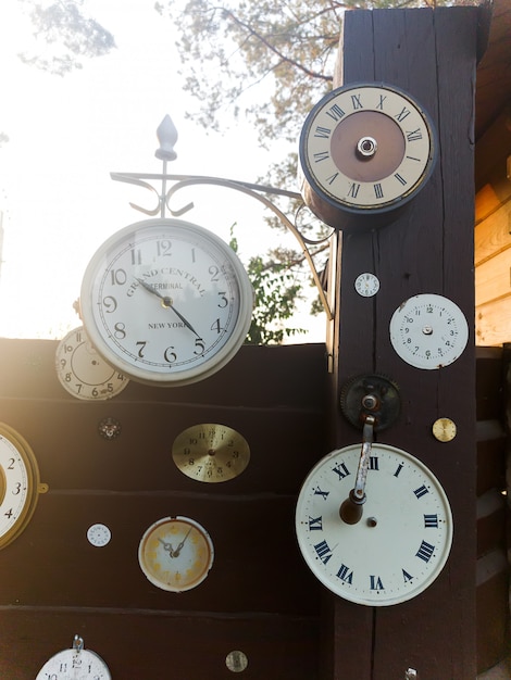Colección de reloj vintage que cuelga en una pared de madera vieja en el aire libre con sol
