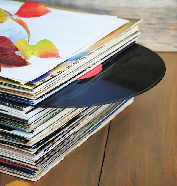 Colección de viejos discos de vinilo en una pila con hojas de otoño.