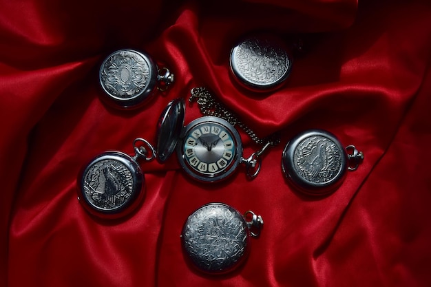 Colección vintage de relojes de bolsillo antiguos sobre fondo rojo arrugado