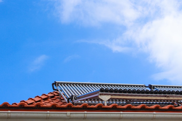 Colectores solares para agua caliente y calefacción en el techo de la casa sobre fondo de cielo azul