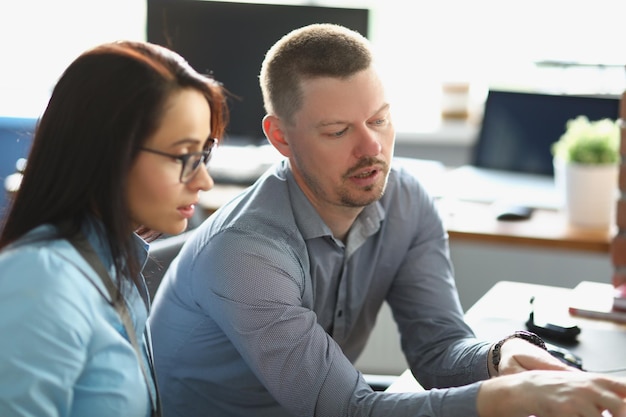 Colega hombre inteligente ayuda a un compañero de trabajo con el proceso de trabajo a explicar algo en la computadora portátil