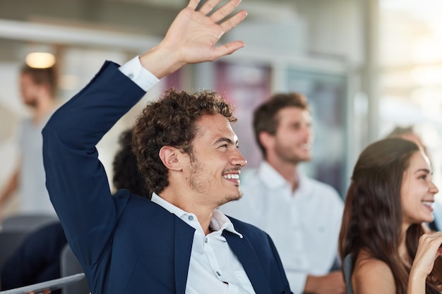 Colega sonriente con la mano levantada durante una reunión en la oficina