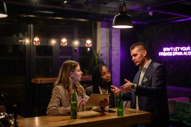 Colegas alegres bebiendo cerveza en el bar juntos después del trabajo