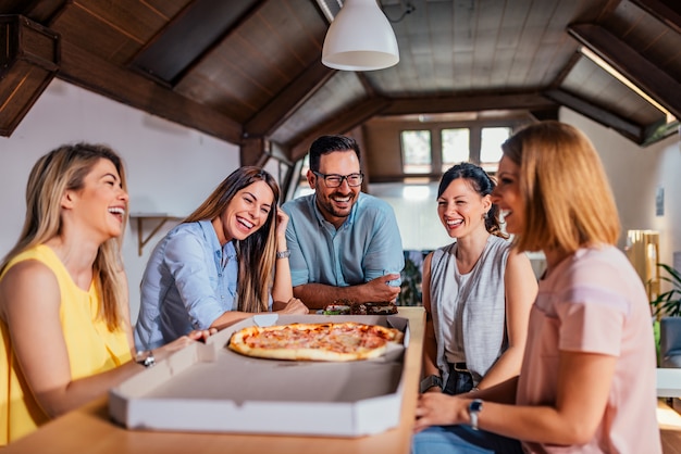 Colegas almorzando, comiendo pizza.