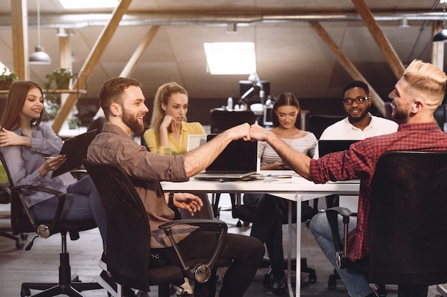 Colegas amigáveis batendo os punhos no local de trabalho compartilhando sucesso