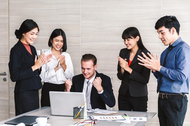 Colegas aplaudindo empresário usando laptop no escritório