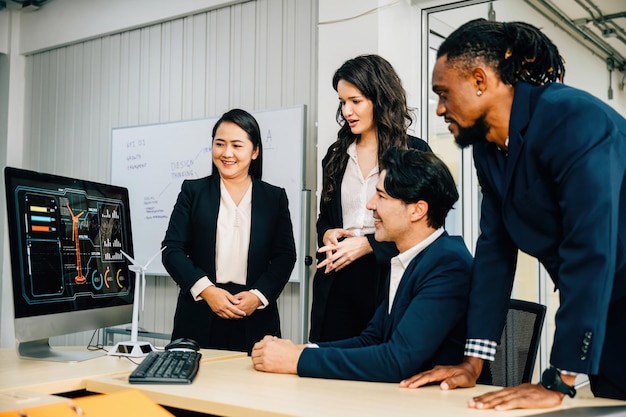 Colegas com conhecimentos variados reúnem-se em torno de um computador de secretária para uma reunião produtiva A sua discussão de trabalho em equipa e liderança promovem uma estratégia de marketing bem sucedida e cooperação