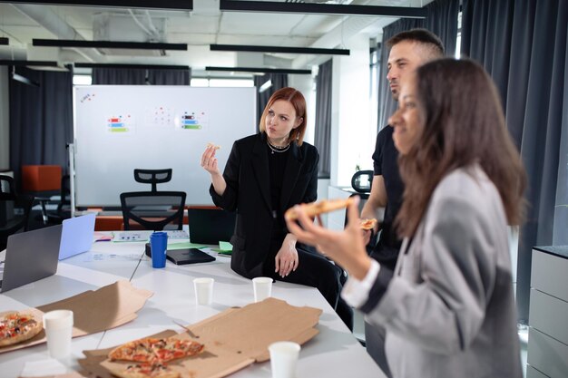 Colegas comem pizza no escritório durante o almoço