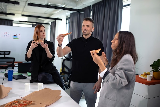 Los colegas comen pizza en la oficina durante el almuerzo