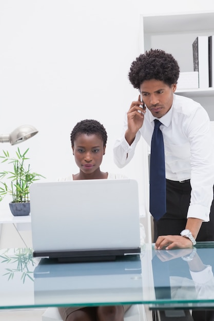 Colegas concentrados usando una computadora portátil y llamando