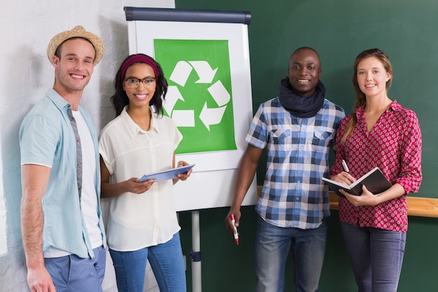 Colegas creativos con símbolo de reciclaje en pizarra