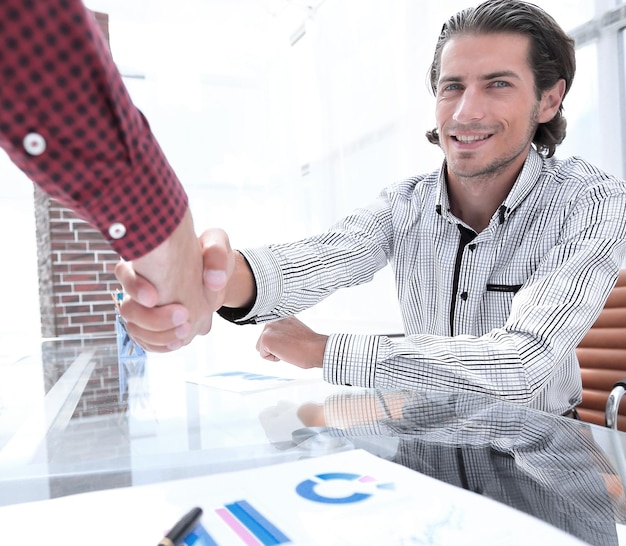 Foto colegas dándose la mano sobre el escritorio en la oficina