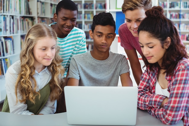 Colegas de classe atentos usando laptop na biblioteca