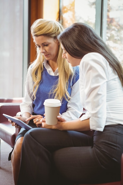 Foto colegas de negócios concentrados segurando copo de café e tablet