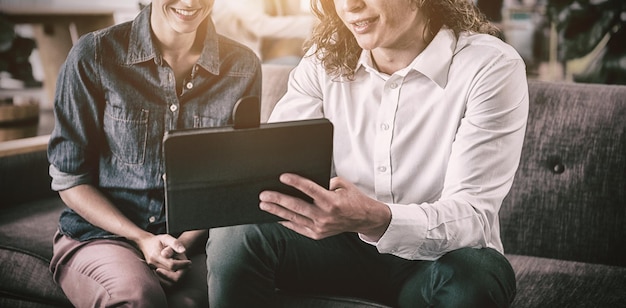 Colegas de trabalho a discutir sobre tablet digital a sorrir