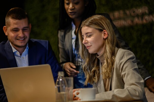 Colegas de trabalho alegres trabalhando em um laptop durante uma reunião em um café