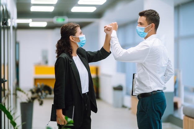 Colegas de trabalho batendo nos cotovelos enquanto se cumprimentam no trabalho.