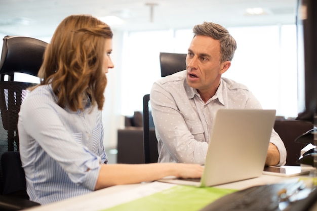 Colegas de trabalho discutindo enquanto trabalham no escritório