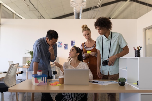 Colegas de trabalho discutindo sobre laptop no escritório