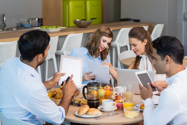 Colegas de trabalho discutindo sobre tablet digital enquanto tomam café da manhã