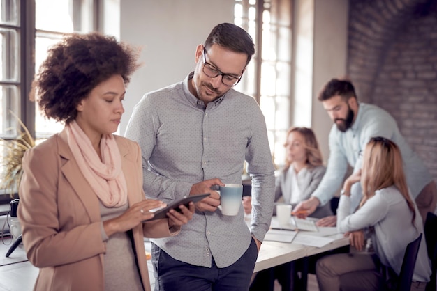 Colegas de trabalho em escritório moderno usando tablet