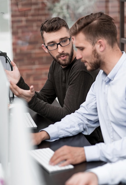 Foto colegas de trabalho falam sentados em uma mesa de computador