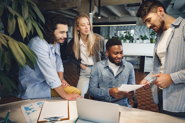Colegas de trabalho multirraciais sorridentes trabalhando juntos em uma reunião de escritório têm uma discussão