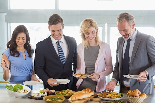 Foto colegas de trabalho, servindo-se no buffet de almoço