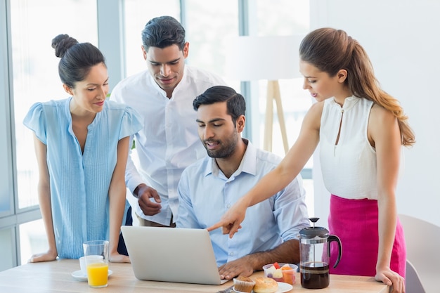 Colegas de trabalho sorridentes discutindo no laptop