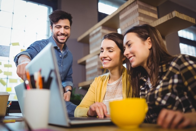 Colegas de trabalho sorrindo enquanto discutia sobre laptop