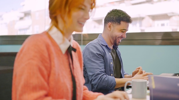 Colegas de trabalho sorrindo enquanto trabalham juntos com computadores