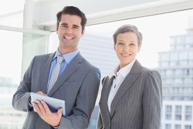 Colegas de trabalho sorrindo na câmera e segurando o tablet